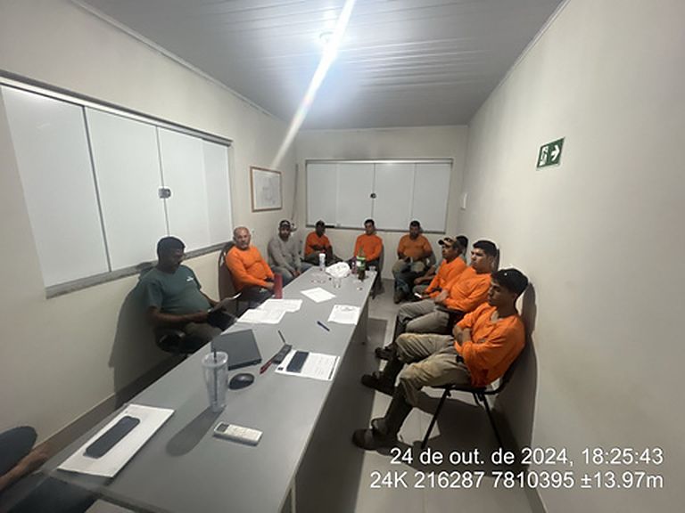 Reunião de equipe em escritório de campo, com registro de data e coordenada